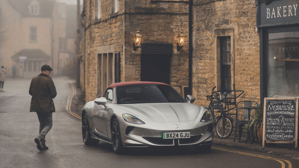 Man approaches parked MG Cyberster outside Cotswold pub